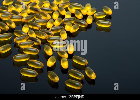 Fischöl Kapseln, gelbe Vitamine auf schwarzem Hintergrund Stockfoto