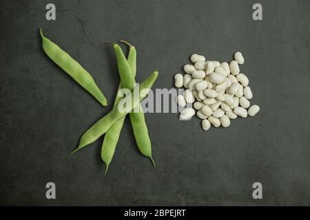 Frische grüne Bohnen und weiße trockene Bohnen auf Beton, Stein Hintergrund. Rohe, gesunde, biologische und schmackhafte Speisen. Flache Lay-Komposition. Stockfoto