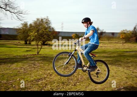 Junge springt mit seinem Dirt Bike über natürliche Rampen im offenen Bereich und genießt Racing Stockfoto