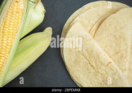 Frisch gebackenes Tortilla Brot und Maiskolben auf Beton, Stein Hintergrund. Köstliche, traditionelle, gesunde Lebensmittel. Draufsicht, flaches Lay-Konzept. Stockfoto