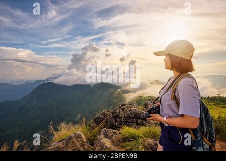 Wanderer asiatische junge Frau glücklich mit Kamera Rucksack und Mützen suchen schöne Landschaft Natur der Berg und bunten Himmel am Sonnenuntergang auf Aussichtspunkt Ph Stockfoto