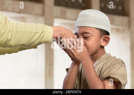 Asiatische muslimische Kind küssen eine Hand von einem alten Menschen in der Moschee Stockfoto