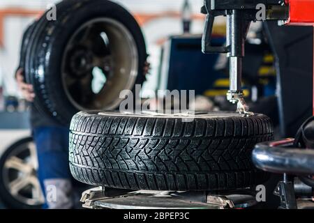 In einer Garage - modernes Auto wartet der Mechaniker seine Räder/Reifen (flachen DOF; getönten Farbbild) ändern Stockfoto