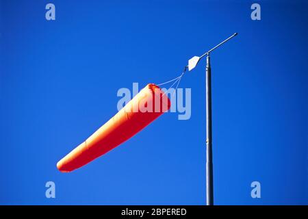 Orangefarbener Windsack bei strahlendem Sonnenschein gegen wolkenlosen blauen Himmel, Lincolnshire, England Stockfoto