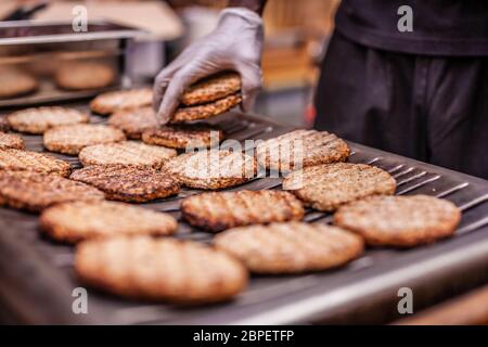 Koch bereitet Burger auf den Grill im freien Stockfoto