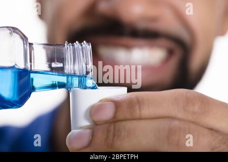 Close-up In eines Mannes Hand gießen Mundwasser in die Kappe Stockfoto