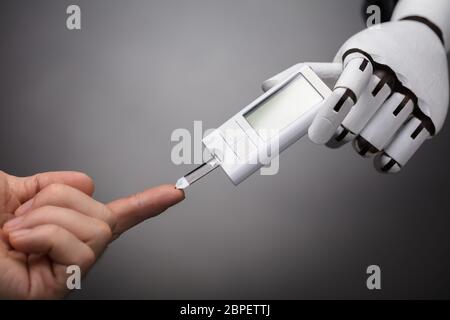 Roboter der Person Blutzucker mit Glucometer auf grauem Hintergrund Stockfoto