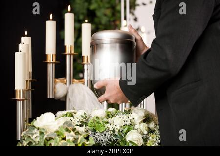 Tod und Qual - Bestattung und Friedhof, mortician, die Urne auf einem Bett aus weissen Rosen Stockfoto