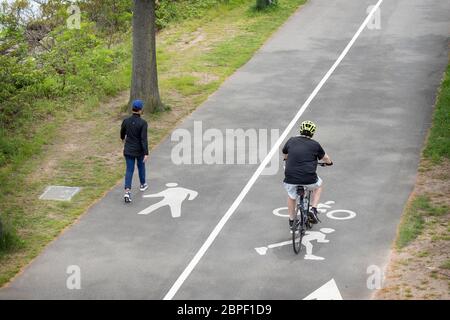 COMPLIANCE. Ein Wanderer und ein Biker trainieren jeweils in ihren ausgewiesenen Bahnen. In der Nähe des Jachthafens Bayside in Queens, New York City. Stockfoto