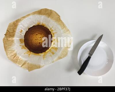 Draufsicht des baskischen gebrannten Käsekuchen und Messer auf einem Teller auf weißem Hintergrund. Stockfoto