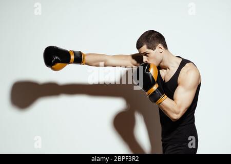 Sportboxer, der mit der rechten Hand einen Schlag wirft, erzeugt einen Schatten auf dem weißen Hintergrund. Stockfoto