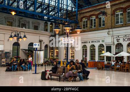 Passagiere warten in Brighton Railway Station vor den Geschäften. Stockfoto