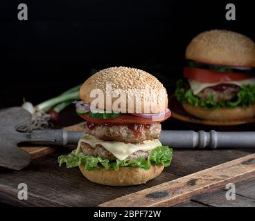 Burger mit zwei gebratene Koteletts, Käse und Gemüse in einer Runde Weizenmehl bun Stockfoto