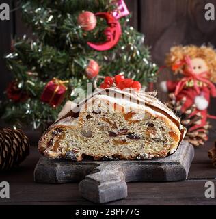 Stollen eine traditionelle europäische Kuchen mit Muttern und kandierten Früchten, mit Puderzucker bestäubt auf braunem Holz- Board Stockfoto