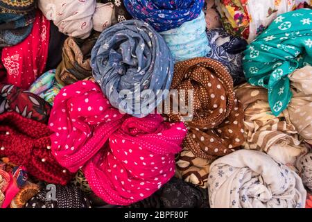 Hintergrund der bunten Frauen Kleidung und Kleider aus vielen Stoffen und Texturen verpackt in einem Street store Anzeige Korb. Keine Menschen. Stockfoto