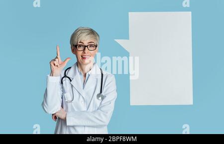 Bekam eine Idee und Arzt Beratung. Frau im weißen Mantel zeigt Finger nach oben, nahe abstrakten Platz zum Denken Stockfoto