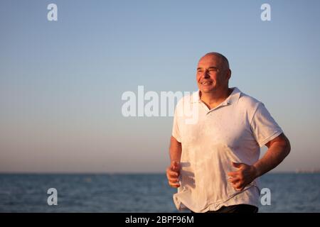 Ein älterer Mann läuft am Meer entlang. Joggen im Resort. Stockfoto