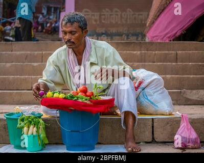 Varanasi, Indien - 11. November 2015. Ein Inder bereitet sich darauf vor, auf den Ghat-Stufen frisches Gemüse an Pilger und Touristen zu verkaufen. Stockfoto