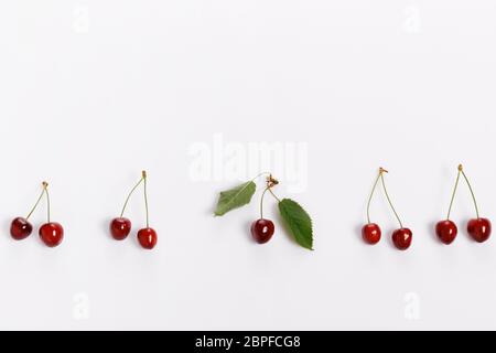 Frische, helle, saftige Kirschen auf weißem Hintergrund, minimalistische Komposition, minimalistisches Thema Stockfoto