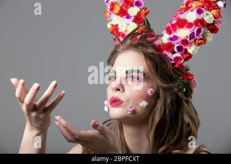 Schöne Blume Mädchen mit Hörnern. Göttin Flora. Schöne Frau mit fantastischen Make-up weht. Frühling Mädchen Modell. Stockfoto