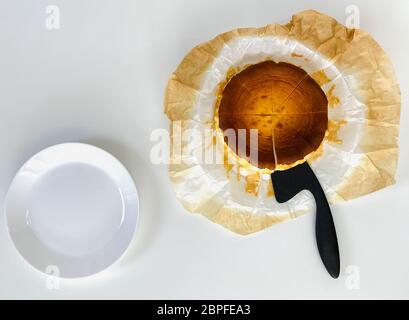 Draufsicht des baskischen gebrannten Käsekuchen mit Kuchenaufstelltisch auf weißem Tisch. Stockfoto