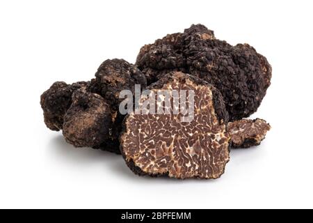 Closeup Schuß von schwarzen Trüffeln und Eichenlaub auf weißem Hintergrund. Stockfoto