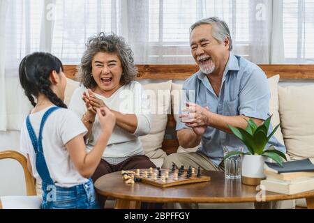 Asiatische Paar Großeltern mit Enkelkind spielen das Schach mit glücklichen Gefühl zusammen, feiern und gewinnen, lang leben und ältere Gesellschaft, warmes fa Stockfoto
