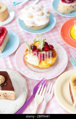 Leckere kleine Kuchen und Torten auf bunten Platten Stockfoto