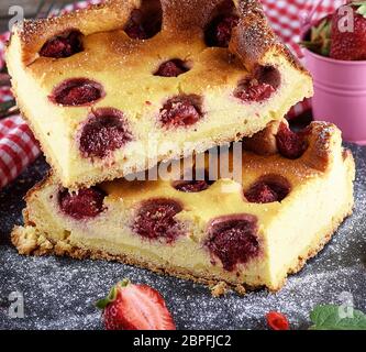 Stücke des Kreisdiagramms aus Quark und Erdbeeren auf schwarzem Graphit Platte Stockfoto