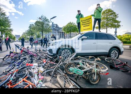 Berlin, Deutschland. Mai 2020. Greenpeace-Aktivisten demonstrieren vor dem Reichstag posiert auf einem Auto, das am 5. Mai über Fahrräder fährt. Gegen eine neue Abwrackprämie für Diesel- und Benzinautos soll anlässlich des Auto-Gipfels im Kanzleramt protestiert werden. Quelle: Michael Kappeler/dpa/Alamy Live News Stockfoto