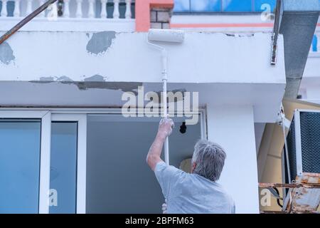 Arbeiter malt ein Gebäude mit weißer Farbe Stockfoto