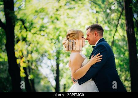 paar Braut und Bräutigam auf dem Hintergrund der Bäume des Parks. Stockfoto