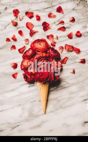 Waffelkegel mit Kugel Ranunculus Blumen über Marmor Hintergrund Stockfoto