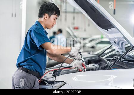 Mechaniker in Asien prüfen und reparieren das Fahrzeug im Wartungszentrum, das Teil von Ausstellungsräumen, Technikern oder Ingenieuren ist Stockfoto