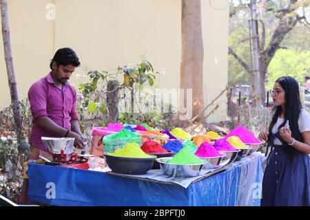 Ein Mädchen in Bolpur Street Market Stall Kauf Pulver trockene Farben auf Holi Festival Anlass. Holi ist berühmt Festival der Farben gefeiert alle indischen Stockfoto