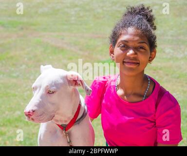 Junger brasilianischer Hundetrainer mit schönem weißen Hund mit großen gelben Augen Stockfoto