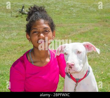 Junger brasilianischer Hundetrainer mit schönem weißen Hund mit großen gelben Augen Stockfoto