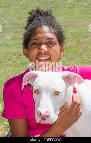 Junger brasilianischer Hundetrainer mit schönem weißen Hund mit großen gelben Augen Stockfoto