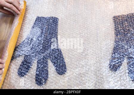 Werkstatt von Hand eine Fleece Handschuhe von blau Merino Schafschurwolle nass Filzen Prozess - Handwerker Brötchen gefilzte Handschuhe mit Holz- Rolling Pin Stockfoto