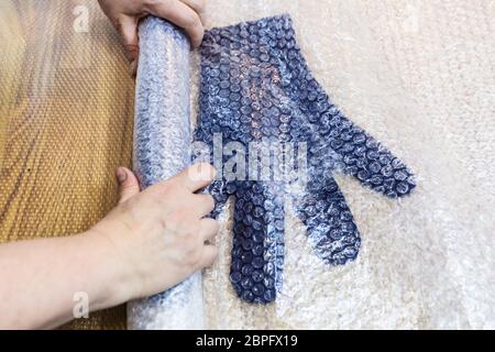 Werkstatt von Hand eine Fleece Handschuhe von blau Merino Schafschurwolle nass Filzen Prozess - Handwerker drückt die gefilzte Handschuhe in Matte für Walken Stockfoto