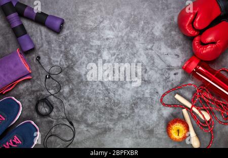 Fitness Stillleben mit Hanteln, Seil, Boxhandschuhen, Sneakers, Wasserflasche und smarten Armband auf grauem Hintergrund. Draufsicht mit Kopierbereich. F Stockfoto