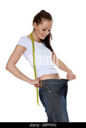 Die schöne junge Frau in alten Jeans nach dem Abnehmen auf weißem Hintergrund. Konzept der gesunden Lebensweise. Stockfoto