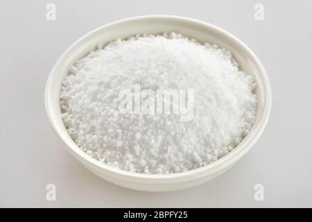 Schüssel aus weißem Fleur de Sel Salz durch Verdunstung an der Oberfläche des Meerwassers über einem weißen Hintergrund Stockfoto