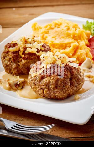 Zwei erfahrene Bayerische Frikadellen oder Masse Rindfleisch Frikadellen mit Zwiebel und Karotte und Kartoffel Begleitung Mischung Stockfoto