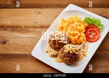 Zwei bayerische Frikadellen oder fleischbällchen von Boden oder Hackfleisch würzigen Fleisch serviert mit Kartoffeln und Karotten mischen mit Salat garniert Stockfoto