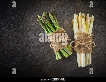 Blumensträuße frischer grüner und weißer Spargel gebunden und Säcken ausgestattet. Draufsicht auf dunklem Hintergrund mit Kopie Raum Stockfoto