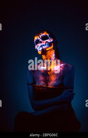 Girl's Gesicht gemalt in fluoreszierende UV-Farben und sieht aus wie Neon leuchtenden Schädel Stockfoto