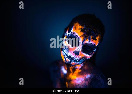 Girl's Gesicht gemalt in fluoreszierende UV-Farben und sieht aus wie Neon leuchtenden Schädel Stockfoto