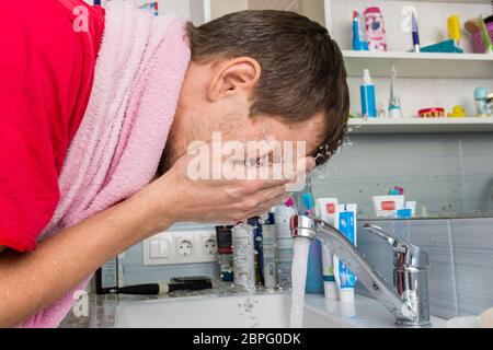 Mann sein Gesicht waschen am Morgen im Badezimmer Stockfoto