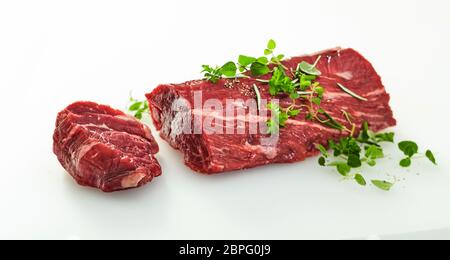 Medaillon in Scheiben geschnitten eine ganze rohe Rinderfilet isoliert auf Weiss und mit Brunnenkresse Kräuter garniert Stockfoto